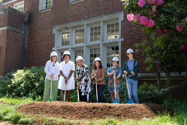 Six people standing in front of North Portland Library with hard hats and shovels in front of a pile of dirt.