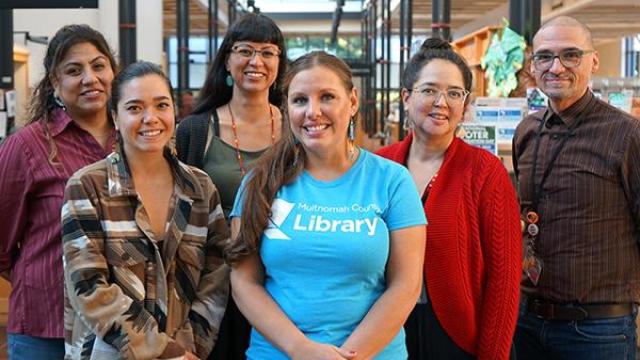 Six members of the Indigenous team inside a library standing with each other smiling