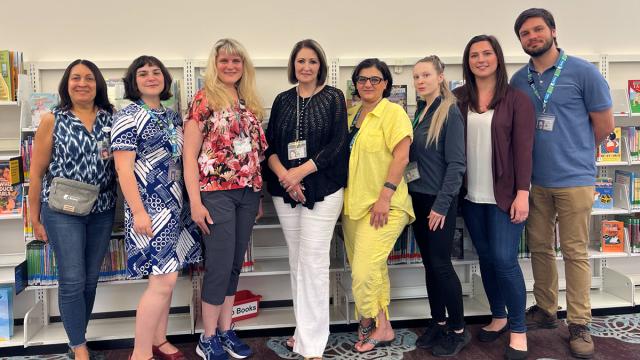 Library staff members standing in front of bookshelves at the library