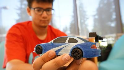Teen at the Rockwood makerspace holding a car in his hand, made with a 3D printer.