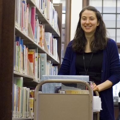 Volunteer in stacks with a book truck