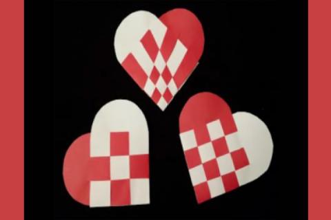 Photograph of red and white hearts made out of paper on a black background.