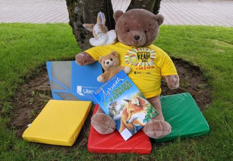 Photograph of stuffed bear wearing a summer reading t-shirt with a giant library card