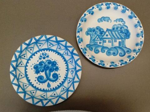 Photograph of two white paper plates with blue painting on them
