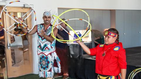 Two people in Native regalia holding hoops in a dance