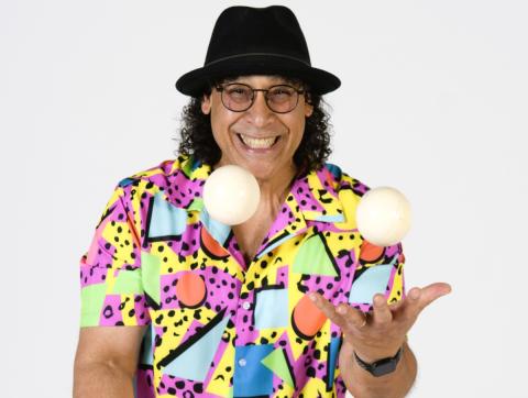 Performer Angel in bright shirt juggling and smiling 