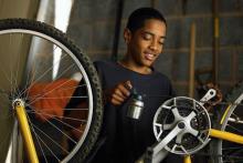 Photograph of a black child working on a bike