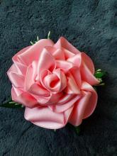 Photograph of a rose-shaped barrette made out pink ribbon