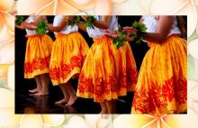 hula dancers from the waist down, in orange skirts, in front of plumeria flowers