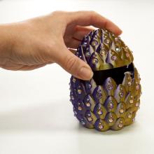 Image of a hand lifting the lid of a dragon egg