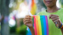 Youth holding a rainbow flag and smiling