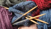 Photo of knitting needles among various colors of yarn