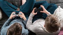 Photo of two kids sitting side by side playing video games.
