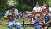 Photo of Newel Briggs performing music outdoors for an audience.
