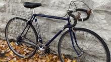 black ten-speed bicycle leaning against a stone wall