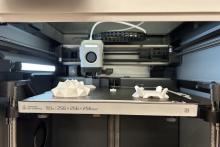 Photo of a Bambu printer working on white projects.