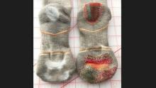 Photo shows two socks one mended with colorful dash embroidery