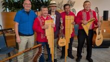 Group of musicians holding various sized panpipe flutes, guitar and Cuatro.