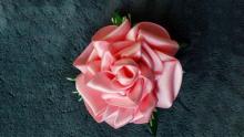 Photograph of a rose-shaped barrette made out pink ribbon