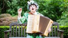 Photo of Maeve Stier with accordian on a park bench