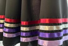 Photo of a black skirt with 4 ribbons sewn at the bottom in lilac, purple, yellow and red.