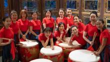 Photo of the Mulan Drum Team with their instruments in red and black attire.