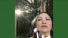 Picture of Renee Roman Nose with Native jewelry against backdrop of forest