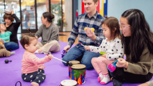 Photo of parents and young children playing with drums