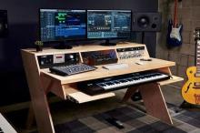 Photo of a desk with a music production setup and monitors