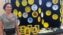 Photo of Lyubov Romanova in front of several different yellow and blue pieces of art.
