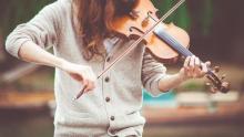 a girl in cardigan playing the violin