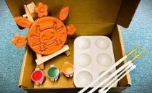 a photograph of a handmade clay axolotl in a box with a paint set