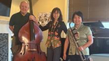 Photo of three members of Hearts Strings Mandarin Trio holding different instruments and smiling.