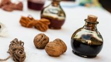 Photo of a jar of walnut ink with walnuts near it on a white table