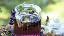 Photo of a glass cup holding a purple drink made of natural lavender sprigs.