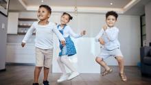 A family of four in matching blue and orange exercise outfits performing a coordinated stretch routine