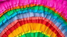 Photo of a rainbow of crepe paper cut into tassel strips for a piñata.