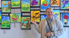 Photo of Liya Kot Kurkov in front of a wall of summer art