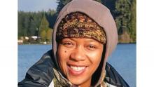 Photo of Sharon in outdoorsy winter clothing with a lake and trees behind her