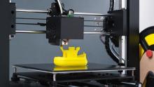 Photo of a 3D printer making a yellow toy boat