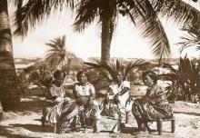 a sepia photo of women sitting outside gathered around a low table with beverages and cups