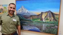 Photo of Erick Rodriguez in front of one of his paintings