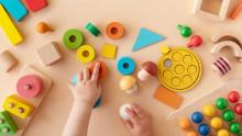 Photo of tiny hands playing with multicolor blocks of many shapes.