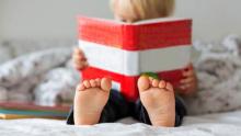 Photo of a toddler reading a red and white striped book