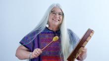 Photo of Karen Kitchen holding a drum and mallet, smiling
