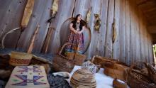 Photo of Stephanie Craig surrounded by basketry and tanned hides