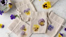 Photo of several beige pull tie bags with natural floral printing pressed into them.