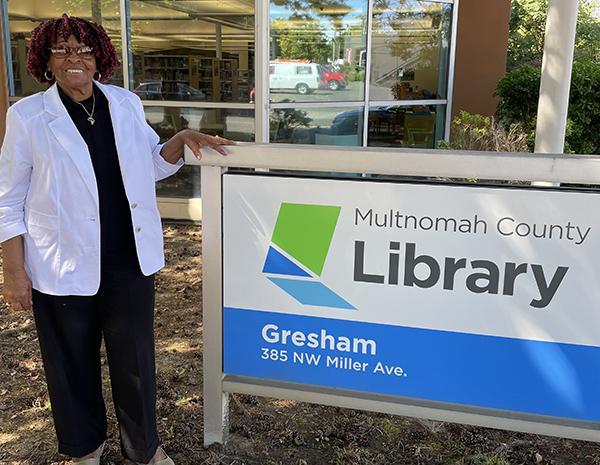 Adult patron standing by sign for Gresham Library