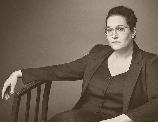 Carmen Maria Machado seated with one hand on back of another chair