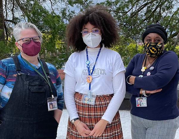 Two teen librarians and one youth librarian wearing face masks face the camera.